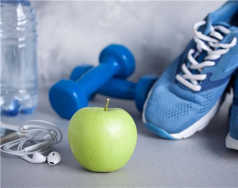 Sport shoes, dumbbells, earphones, apple, bottle of water, concrete background