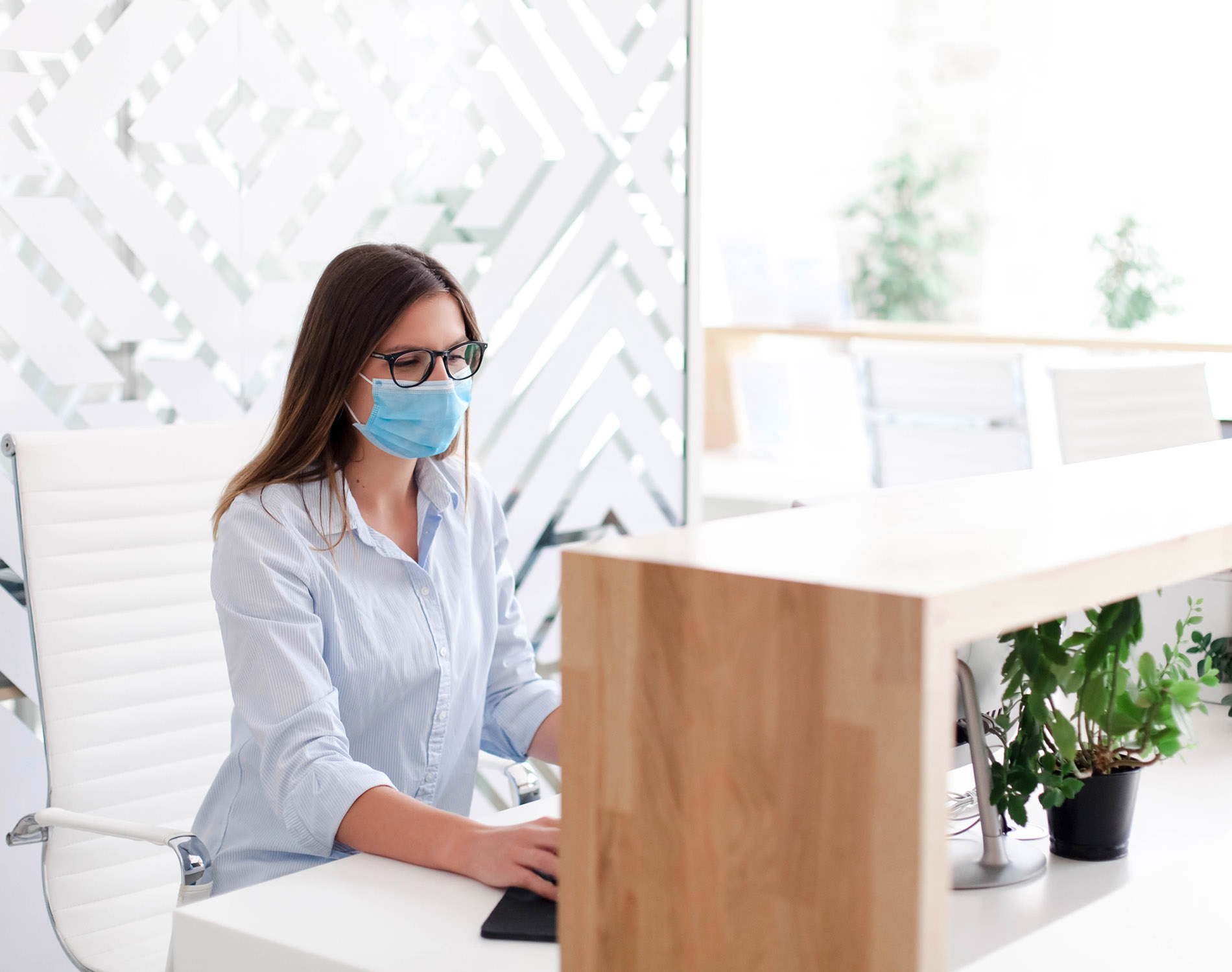 Woman wearing mask sitting at reception desk