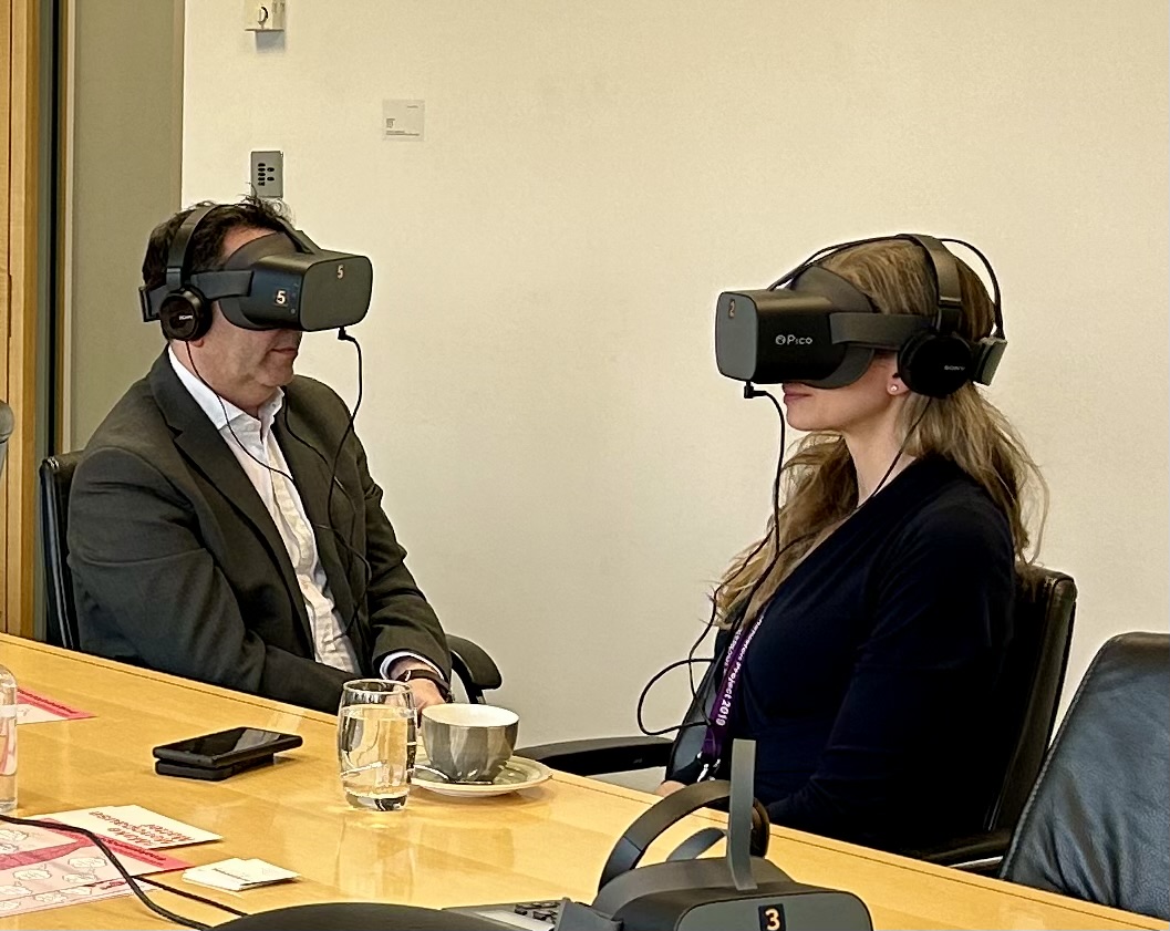 Director of Clients & Markets for the UK, Ireland and Middle East, Damian Taylor, sits opposite to Regulatory partner, Katharine Harle. Both are wearing VR headsets, as part of the Menopause reality in the workplace session.