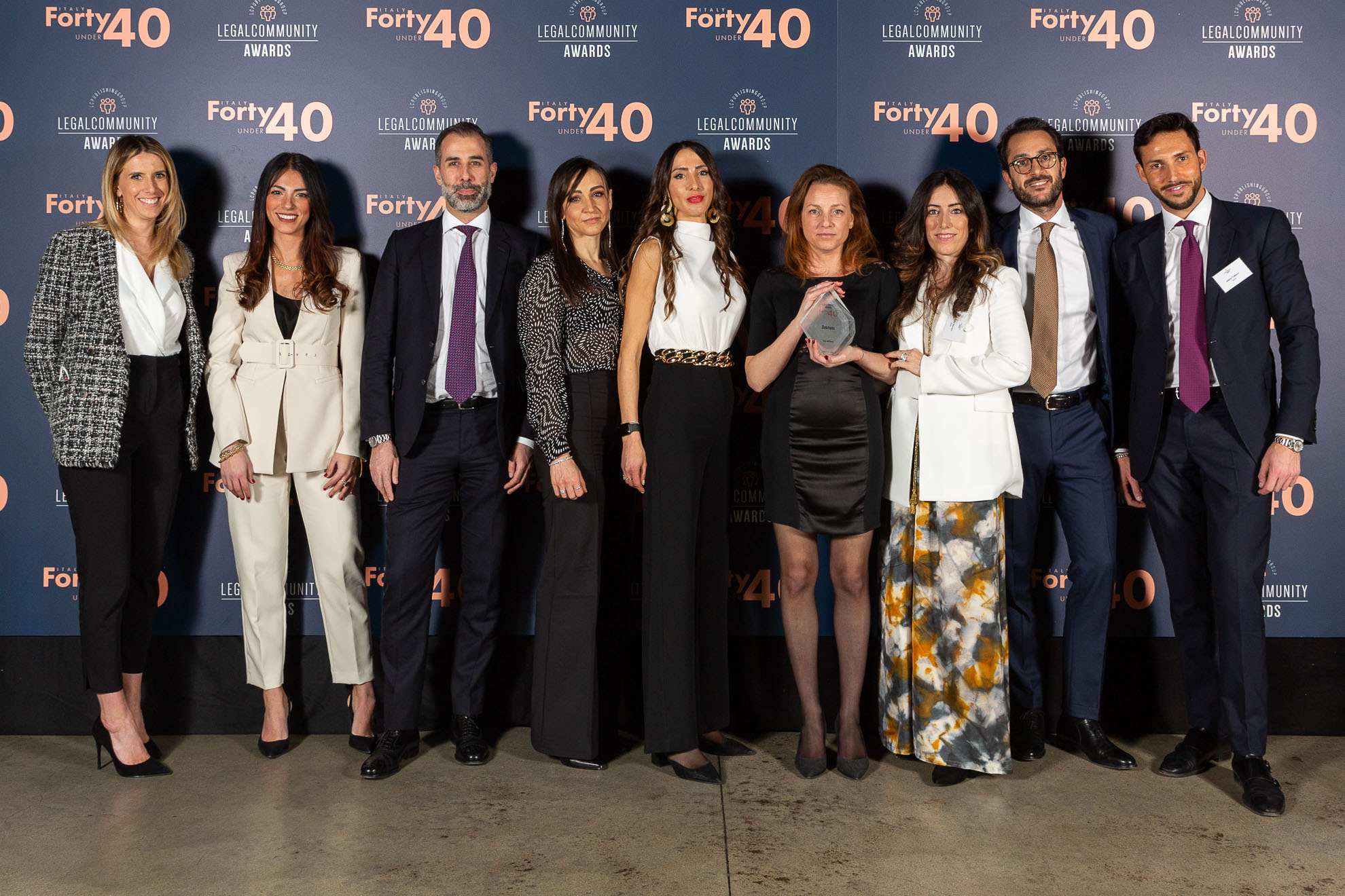 Group of people standing in front of a Legal Community Awards wall