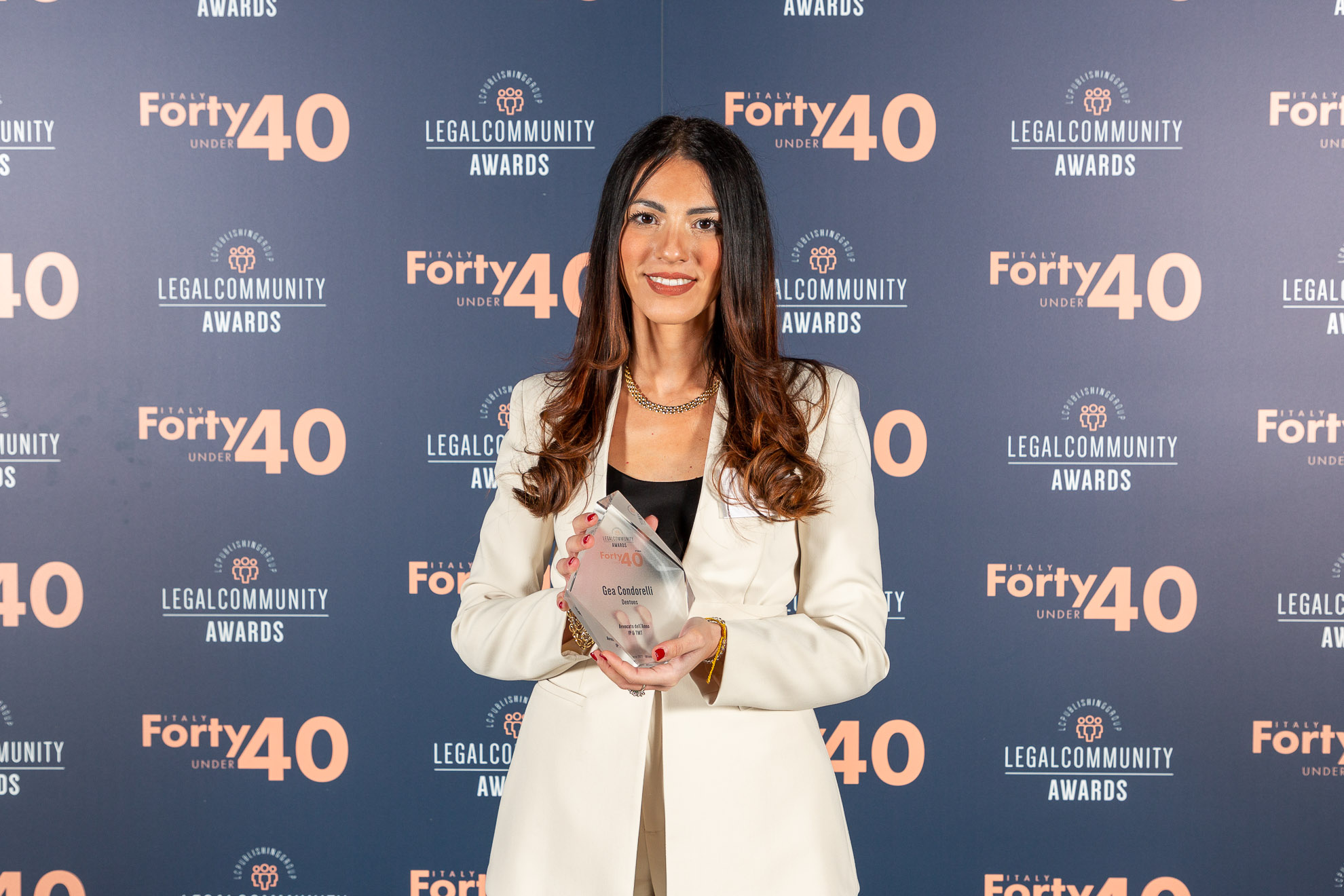 Gea Condorelli standing in front of a wall and holding an Legal Community award in her hands
